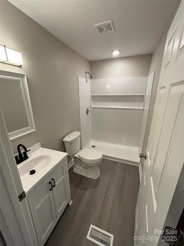 bathroom featuring toilet, hardwood / wood-style flooring, vanity, and a shower