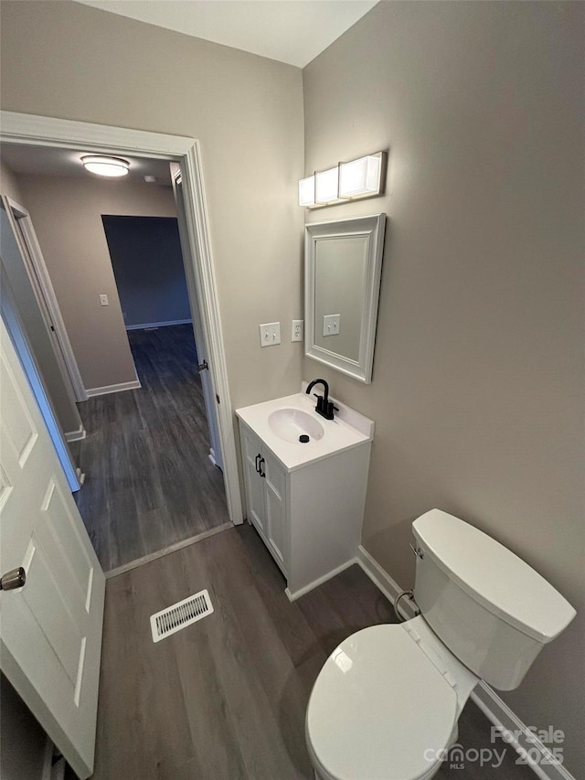 bathroom featuring toilet, vanity, and wood-type flooring