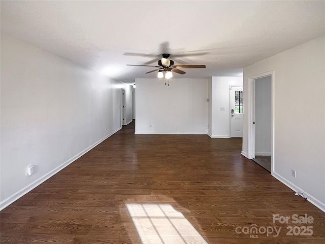 empty room featuring ceiling fan, dark wood-style flooring, and baseboards