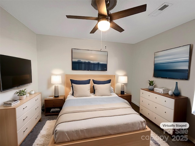 bedroom with dark colored carpet, visible vents, and a ceiling fan