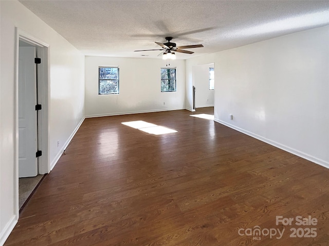 spare room featuring dark wood-style floors, ceiling fan, baseboards, and a textured ceiling