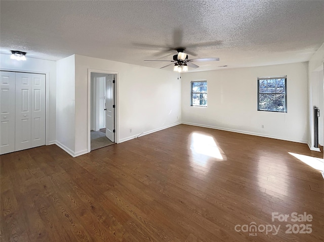 interior space featuring dark wood-type flooring, a textured ceiling, baseboards, and a ceiling fan