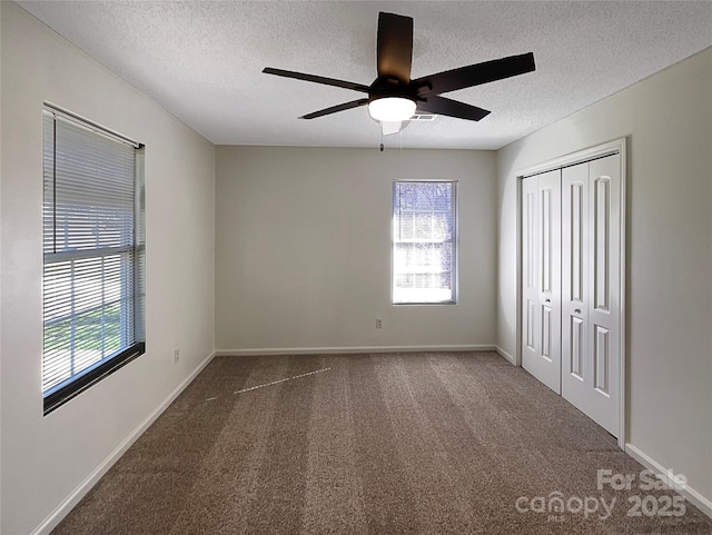 unfurnished bedroom featuring multiple windows, dark carpet, and a closet