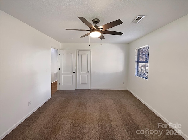 spare room featuring baseboards, visible vents, ceiling fan, a textured ceiling, and dark carpet