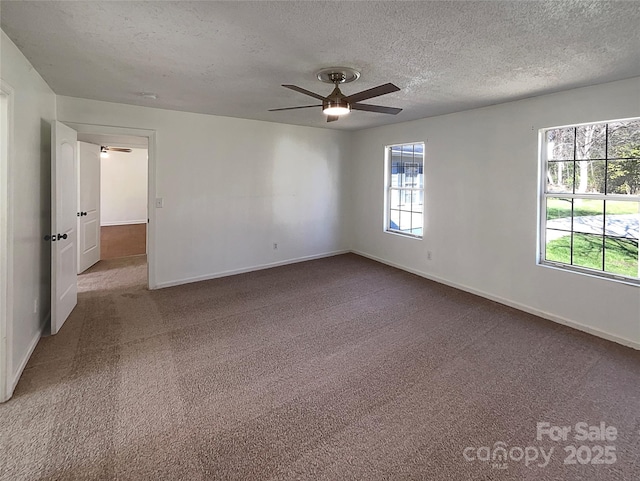 carpeted spare room featuring ceiling fan, baseboards, and a textured ceiling