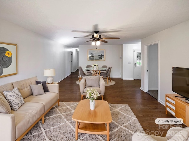 living area with dark wood-style floors, baseboards, and a ceiling fan