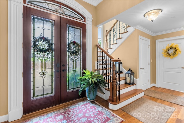 entryway with french doors, crown molding, and wood finished floors