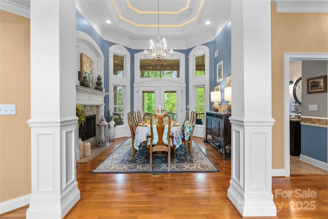 dining area with light wood-type flooring, a tray ceiling, french doors, and a notable chandelier