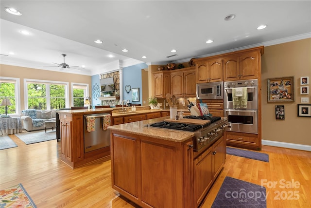 kitchen with a kitchen island, open floor plan, a peninsula, stainless steel appliances, and a sink