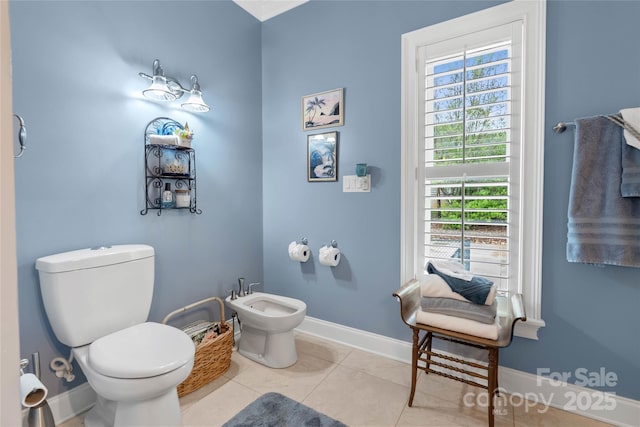 bathroom with baseboards, a bidet, toilet, and tile patterned floors