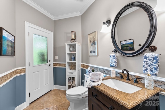 bathroom featuring toilet, a wainscoted wall, tile patterned floors, crown molding, and vanity