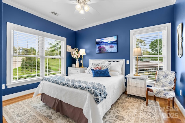 bedroom featuring baseboards, light wood-style flooring, visible vents, and crown molding