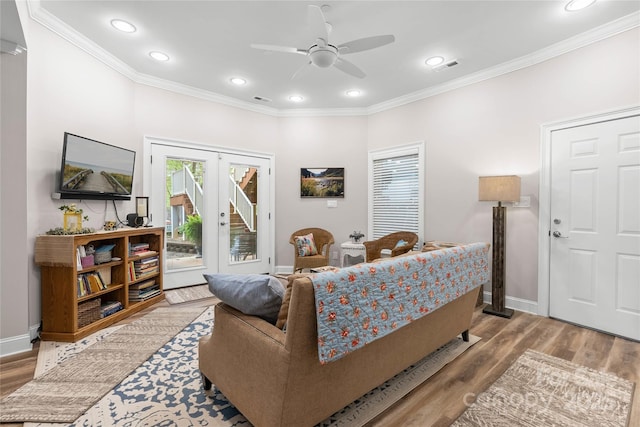 living room with light wood finished floors, baseboards, visible vents, and ornamental molding