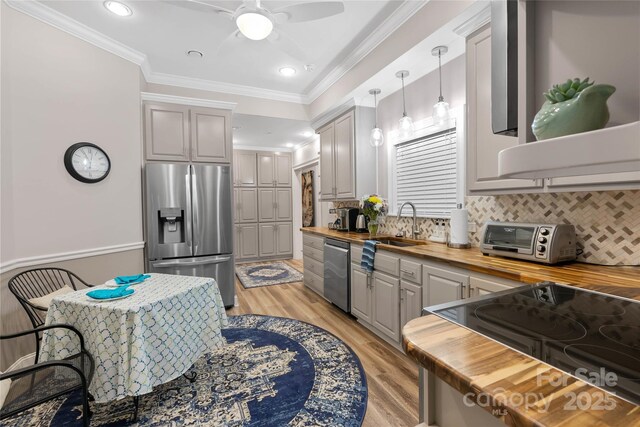 kitchen with pendant lighting, a toaster, crown molding, stainless steel appliances, and wooden counters