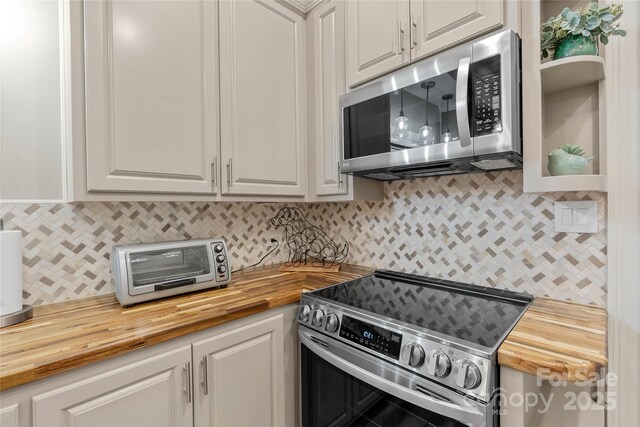 kitchen with stainless steel appliances, white cabinets, and wood counters