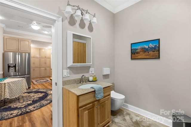 bathroom featuring crown molding, toilet, vanity, wood finished floors, and baseboards