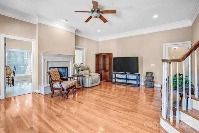 sitting room featuring light wood-style flooring, stairs, crown molding, and a high end fireplace