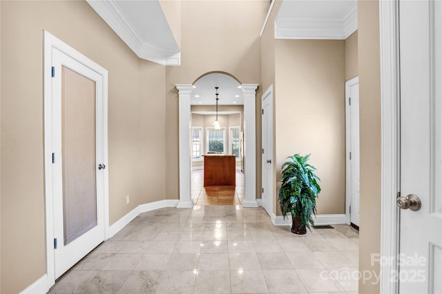 hallway with ornamental molding, arched walkways, baseboards, and ornate columns