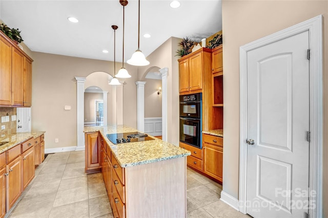 kitchen with a center island, pendant lighting, arched walkways, decorative columns, and black appliances