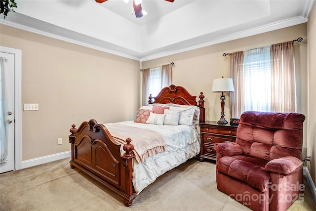 bedroom featuring light colored carpet, a ceiling fan, baseboards, a tray ceiling, and crown molding