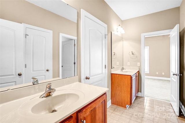 full bath with baseboards, two vanities, a sink, and tile patterned floors