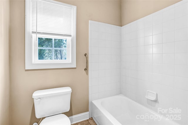 bathroom featuring baseboards, shower / bathing tub combination, and toilet