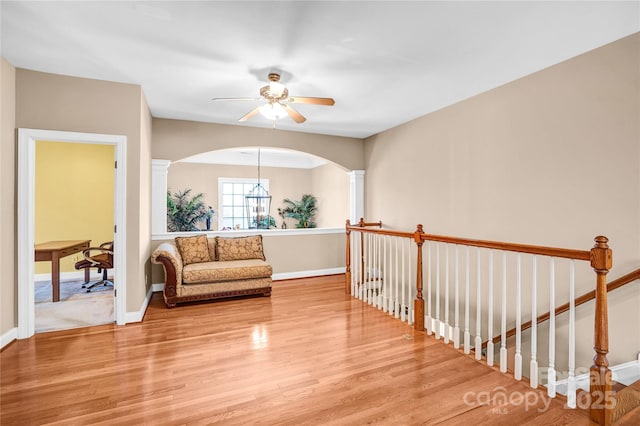 living area with an upstairs landing, decorative columns, baseboards, and wood finished floors