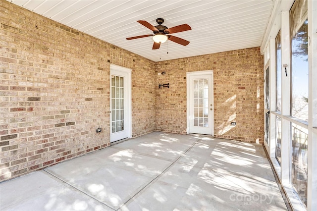 unfurnished sunroom with a ceiling fan and french doors