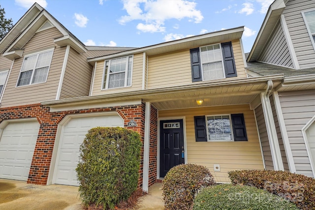 multi unit property featuring a garage, driveway, and brick siding