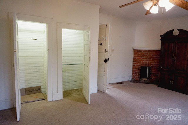 unfurnished living room with light carpet, a brick fireplace, and ceiling fan