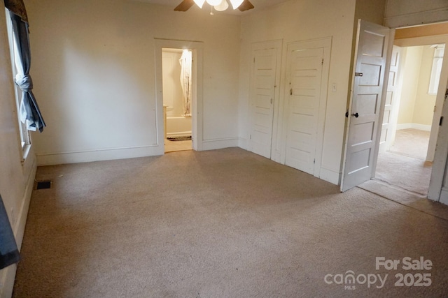 unfurnished bedroom featuring light carpet, ensuite bathroom, ceiling fan, and a closet