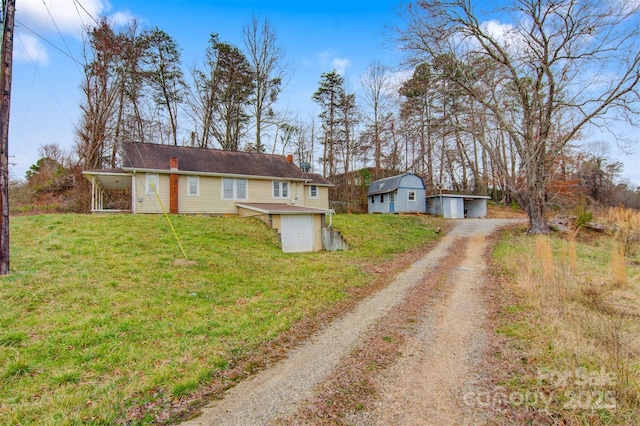 view of front facade with dirt driveway, a front lawn, and an outdoor structure