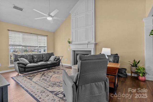 living area featuring a fireplace, wood finished floors, visible vents, baseboards, and a ceiling fan