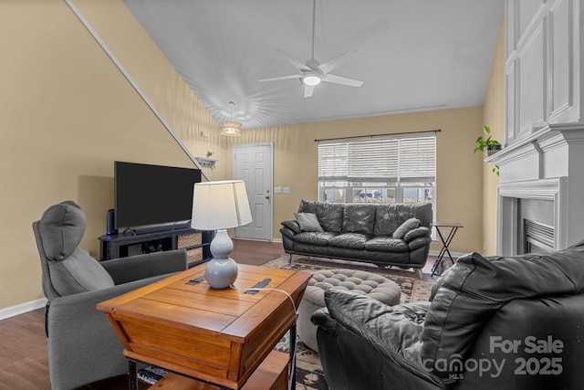 living area with vaulted ceiling, a fireplace, wood finished floors, and a ceiling fan