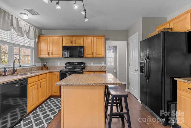 kitchen with a sink, visible vents, dark wood-style floors, black appliances, and a kitchen bar