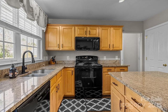 kitchen featuring black appliances, a sink, and light stone countertops