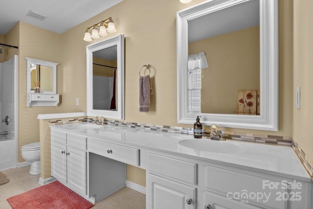 bathroom featuring toilet, double vanity, a sink, and visible vents