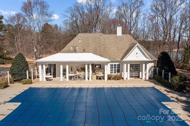 exterior space with a patio area, a chimney, fence, and a fenced in pool