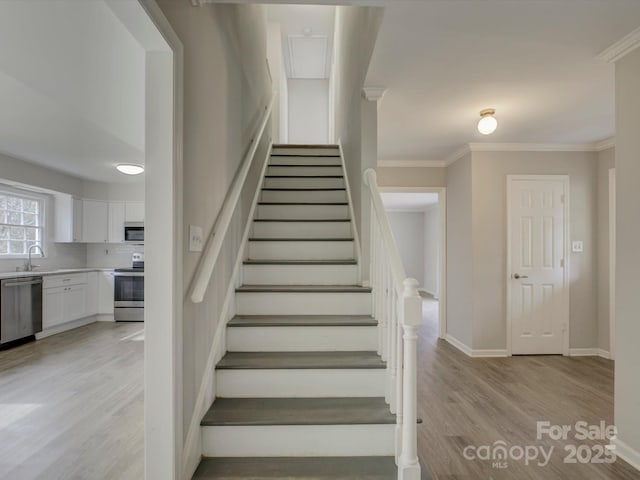 stairs with crown molding, baseboards, and wood finished floors