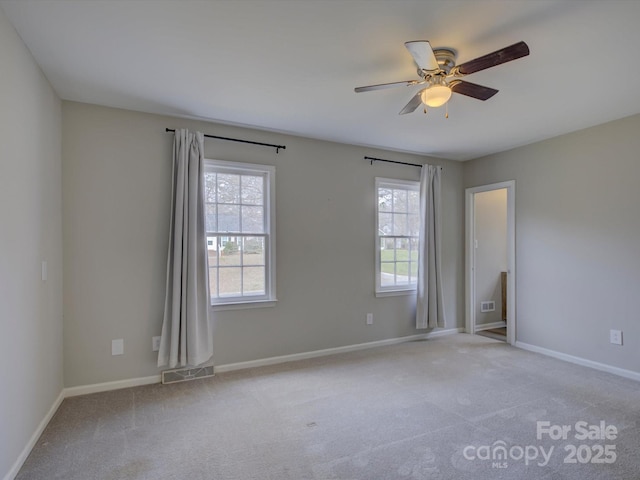 empty room with a healthy amount of sunlight, visible vents, and light colored carpet