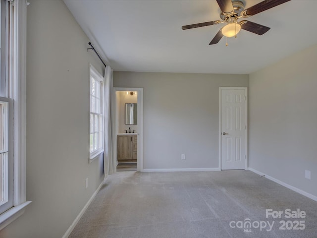 spare room featuring a ceiling fan, light carpet, a sink, and baseboards