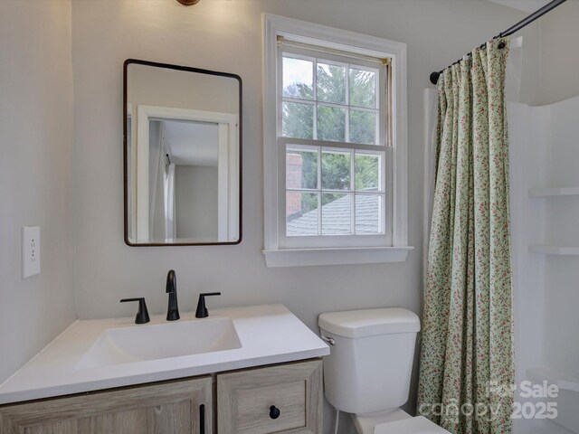 bathroom with curtained shower, vanity, and toilet