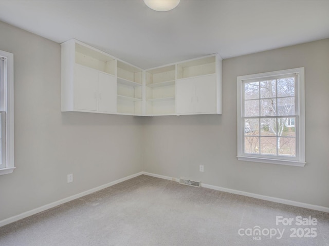 carpeted spare room with visible vents and baseboards