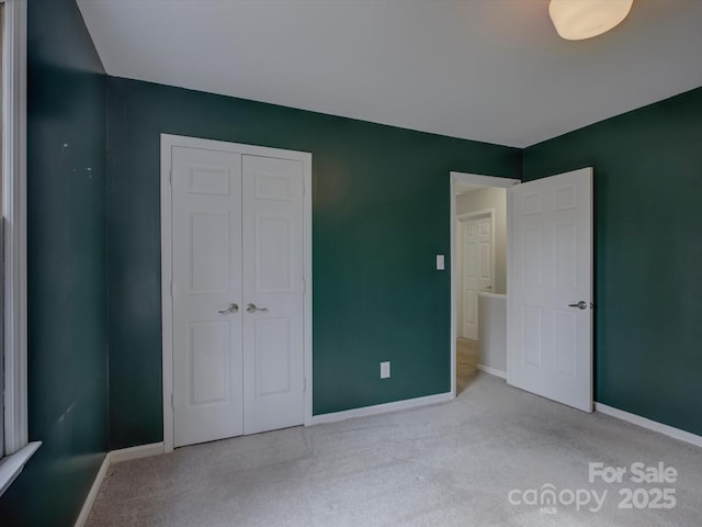 unfurnished bedroom featuring carpet, a closet, and baseboards