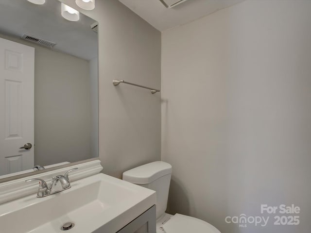 bathroom featuring toilet, visible vents, and vanity