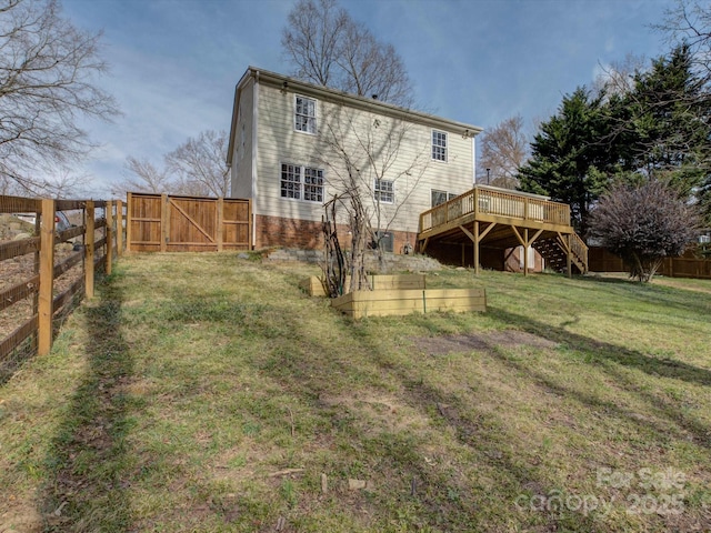 rear view of property with a lawn, a gate, a deck, a fenced backyard, and stairs