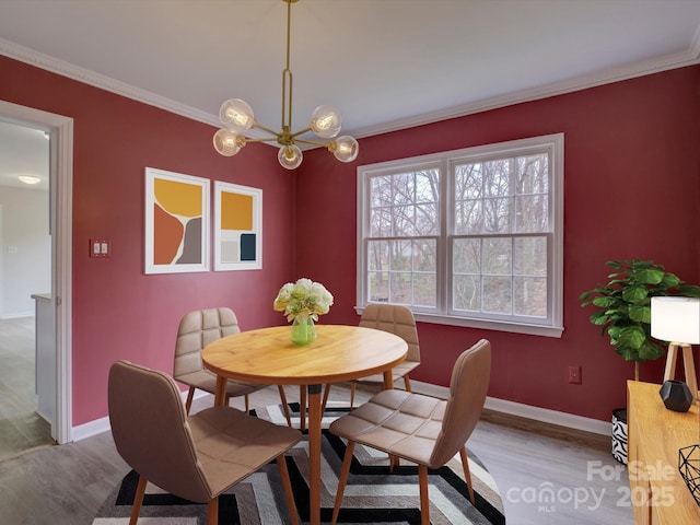 dining room featuring a chandelier, ornamental molding, baseboards, and wood finished floors