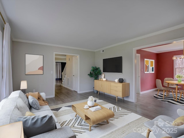 living area with an inviting chandelier, crown molding, baseboards, and wood finished floors