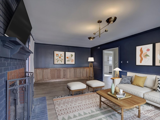 living room with a wainscoted wall, crown molding, and wood finished floors