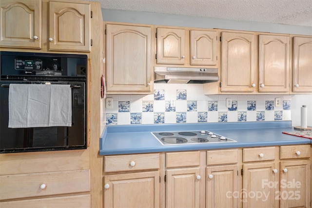 kitchen featuring oven, under cabinet range hood, light countertops, light brown cabinetry, and cooktop